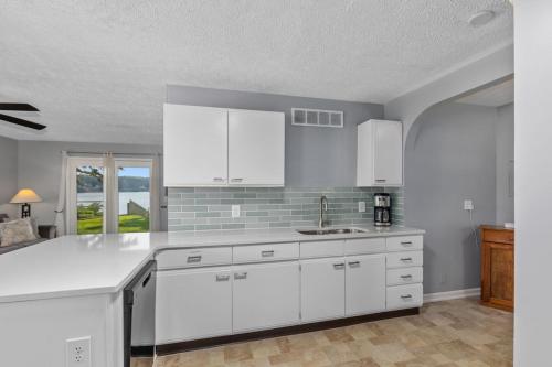 a kitchen with white cabinets and a sink at 2 Lakefront Cottages with Docks, Bikes, BBQ in Newaygo