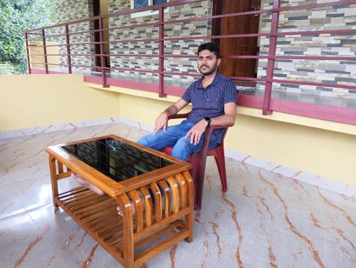 un hombre sentado en una silla junto a una mesa en Tunga Teera, en Sringeri
