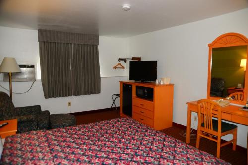 a hotel room with a bed and a desk and a television at Budget Inn Express in Gillette