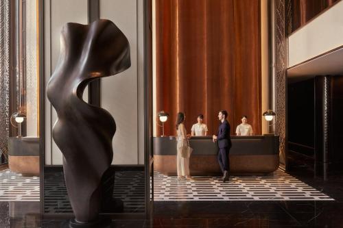 a man and woman standing in a lobby with a sculpture at InterContinental Bangkok Sukhumvit by IHG in Bangkok