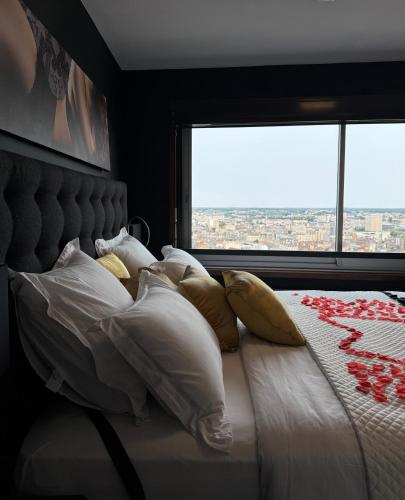 a bedroom with a bed with pillows and a window at Love Horizons - Suite vue panoramique - Spa privatif - Rennes Centre in Rennes