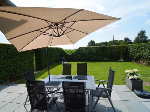 a table and chairs with an umbrella on a patio at Comfortable Home with Sauna in Flobecq