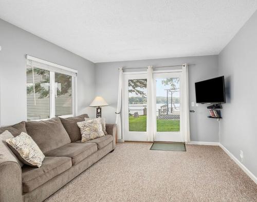 a living room with a couch and a flat screen tv at Waterfront Suite with Dock, Firepit, BBQ in Newaygo