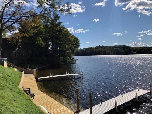 a dock on a lake with trees and clouds in the sky at Waterfront Suite with Dock, Firepit, BBQ in Newaygo