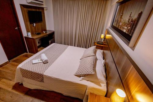 a bedroom with a bed with a phone on it at Padom Business Hotel in Bragança Paulista