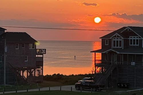 a sunset over the water with a house and a truck at Deja Blue 917 in Frisco