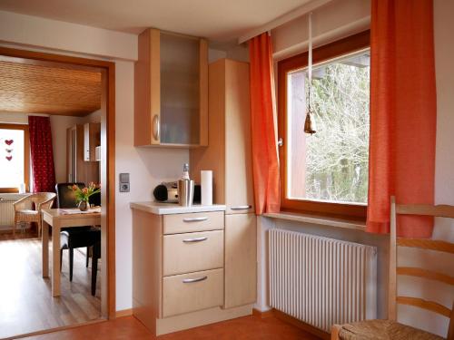 a kitchen with orange curtains and a table and a window at Haus Jurisch in Urberg