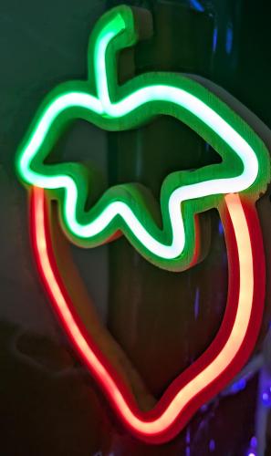 a close up of a green and red neon apple sign at いちごの里祭り村 in Shizuoka