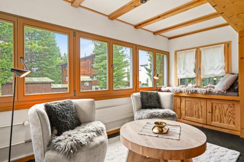 a living room with two chairs and a table and windows at A&Y Chalet Davos Central in Davos