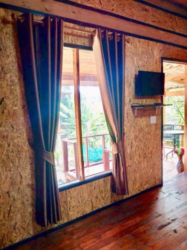 a room with two windows with blue curtains at Wooden House Koh Lanta in Ko Lanta