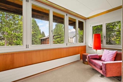 a room with a red chair and windows at A&Y Chalet Davos Central in Davos