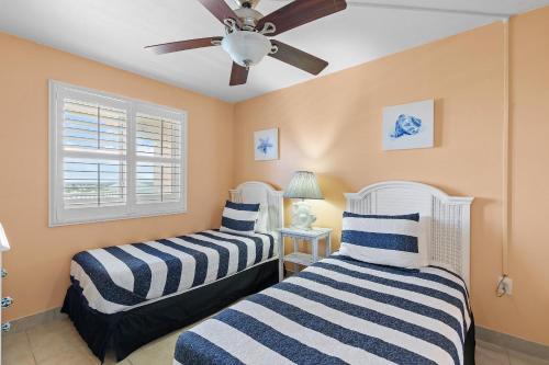 two beds in a room with a ceiling fan at Oceania Plaza 808 in New Smyrna Beach