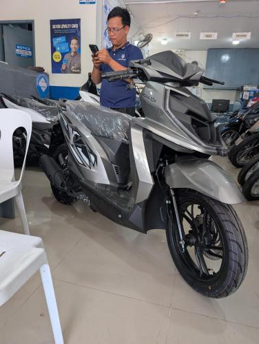 a man is looking at his cell phone next to a motorcycle at B'lu Bamboo in Moalboal