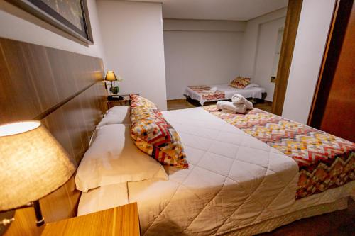 a hotel room with two beds and a lamp at Padom Business Hotel in Bragança Paulista
