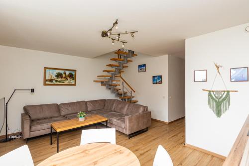 a living room with a couch and a spiral staircase at Apartamentai NEMUNAS in Pervalka