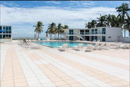Una piscina con tumbonas y un edificio. en UNIT #1108 Castle Beach Club Condominium, en Miami Beach