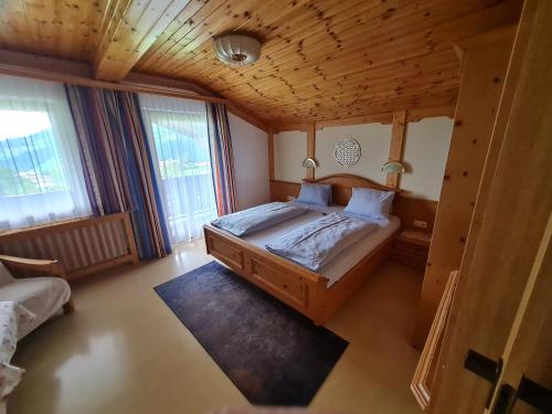 a bedroom with a large bed with a wooden ceiling at Sportpension Alpenrose in Schladming