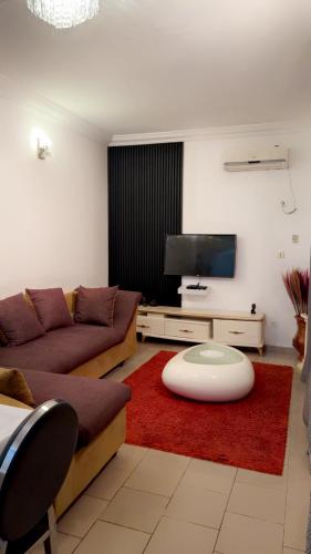 a living room with a couch and a flat screen tv at Résidence Hôtelière l'Océane in Kribi