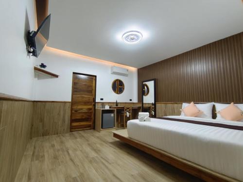 a bedroom with a large bed and a desk at ตัง โฮเทล in Ban Rai Som