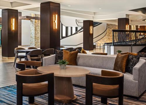 a lobby with a couch and tables and chairs at Marriott Bloomington Normal Hotel and Conference Center in Bloomington