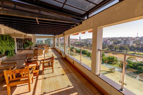 a balcony with wooden tables and chairs and windows at Padom Business Hotel in Bragança Paulista