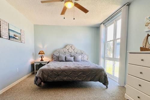 a bedroom with a bed with a ceiling fan and a window at Bombora Suites #202 | Flamingo Suite in Flagler Beach