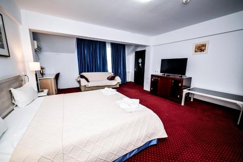 a hotel room with a large white bed and a television at Visconti Militari in Bucharest