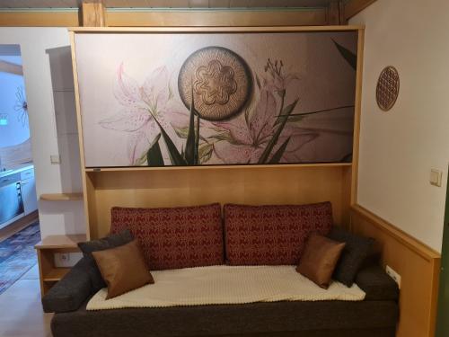 a couch in a living room with a painting on the wall at Sportpension Alpenrose in Schladming