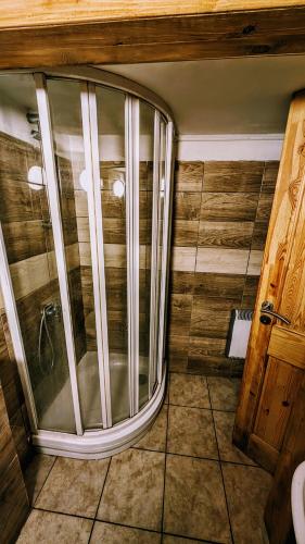 a shower in a room with a wooden wall at CHATA HRABOVO nad jazerom in Ružomberok