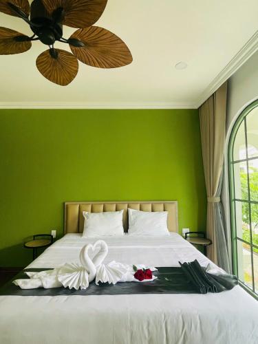 a green bedroom with a bed with two swans on it at La isla Apartments & Villas - Sea View & Fireworks Phu Quoc in Phu Quoc