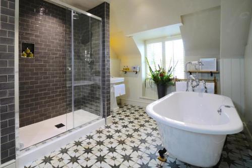 a bathroom with a shower and a tub and a sink at The Bull Hotel in Fairford