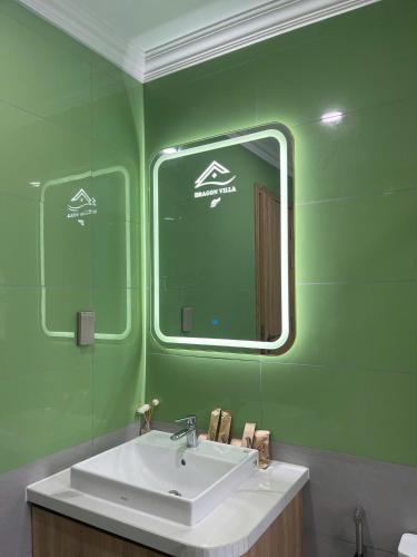 a green bathroom with a sink and a mirror at La isla Apartments & Villas - Sea View & Fireworks Phu Quoc in Phu Quoc