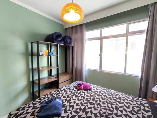 a bedroom with a bed and a book shelf and a window at Studio 3 Praias in São Vicente