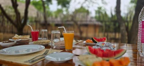 a wooden table topped with plates of food and orange juice at mk yala safari and guest house in Tissamaharama