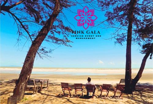 a man sitting at a table on the beach at INAP DESA Homestaycation Kuantan - 5 minutes from Balok Beach by PG Management in Kampong Tanjong