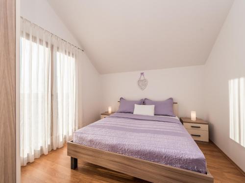 a white bedroom with a large bed with purple sheets at Apartment in Vrsi near the Sea in Vrsi