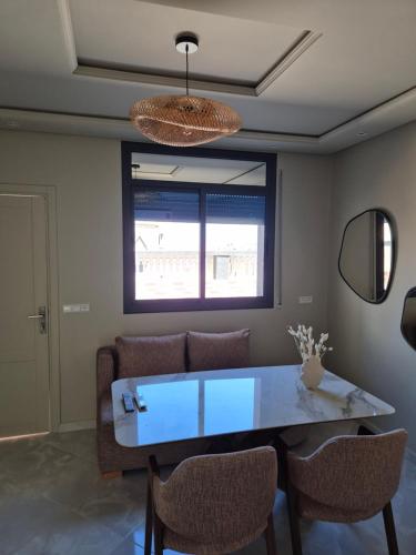 a dining room with a glass table and chairs at Darmoucha in Al Hoceïma