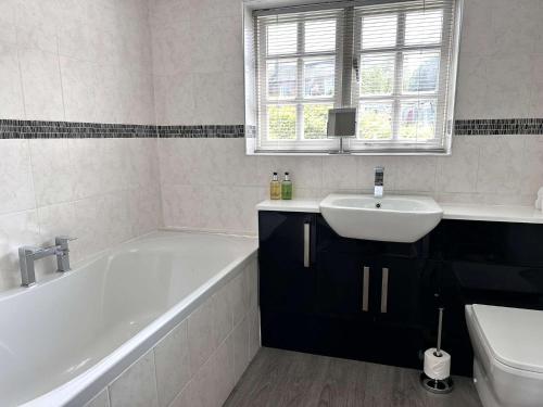 MAYS COTTAGE - Blakeney في بلايكيني: حمام مع حوض استحمام أبيض ومغسلة