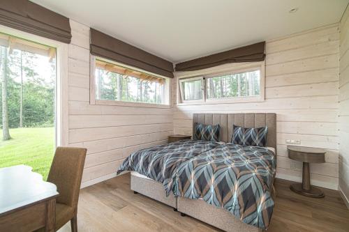 a bedroom with a bed and a desk and windows at Royal Horse Resort in Balkasodis