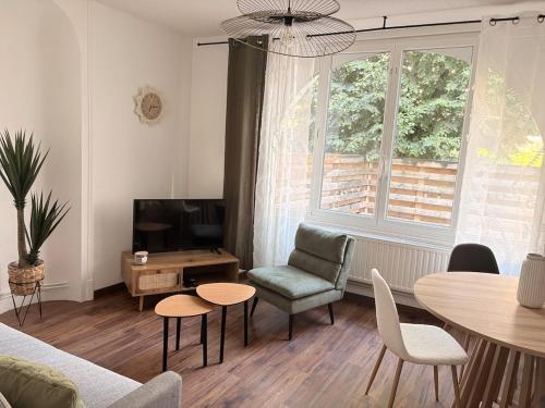 a living room with a couch and a table and a tv at Le Clos Mignon in Besançon