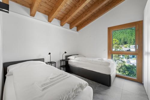 two beds in a white room with a window at Abitaziun Stauffacherin 3 - Pontresina in Pontresina