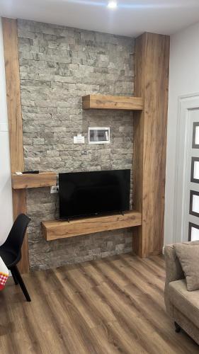 a living room with a television on a brick wall at Apartaments Rene & Devin in Pogradec