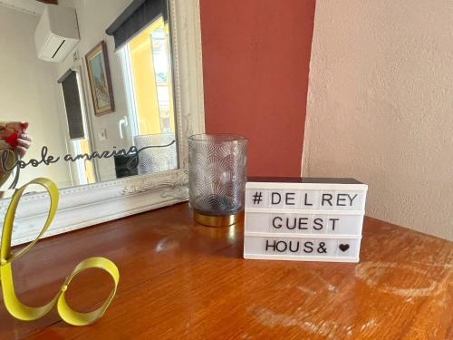 a wooden table with a glass and a sign on it at DEl Rey Guest House in Tomar