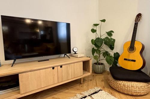 a living room with a guitar and a flat screen tv at Le Catalpa in the heart of a farmhouse in Mittelhausbergen
