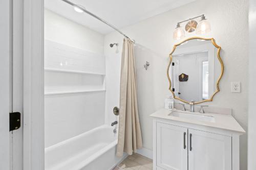 a white bathroom with a sink and a mirror at Chasing Sunsets by Coastline Vacation Rentals in Port Saint Joe
