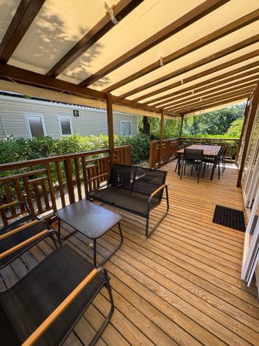 a wooden deck with chairs and tables on it at Bienvenue chez Jean in Condrieu