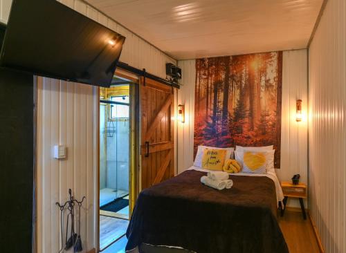 a bedroom with a bed and a painting on the wall at Recanto Lira 2 in Monte Verde