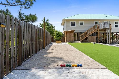 a fence with colorful balls on the ground in front of a house at Stay Salty by Coastline Vacation Rentals in Cape San Blas