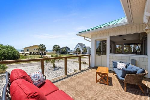 a patio with a red couch and chairs on a balcony at Stay Salty by Coastline Vacation Rentals in Cape San Blas