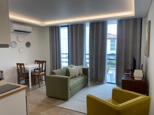 a living room with a green couch and a table at Casa Flor d`Angra in Angra do Heroísmo
